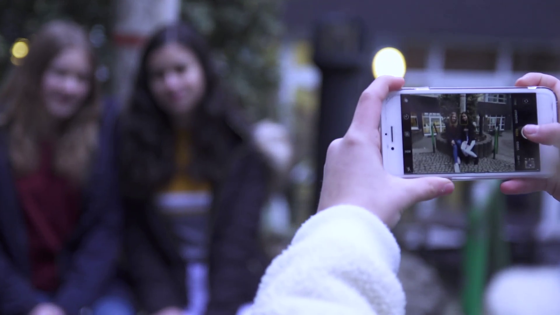 Man sieht, wie jemand Fotos von zwei Freundinnen macht