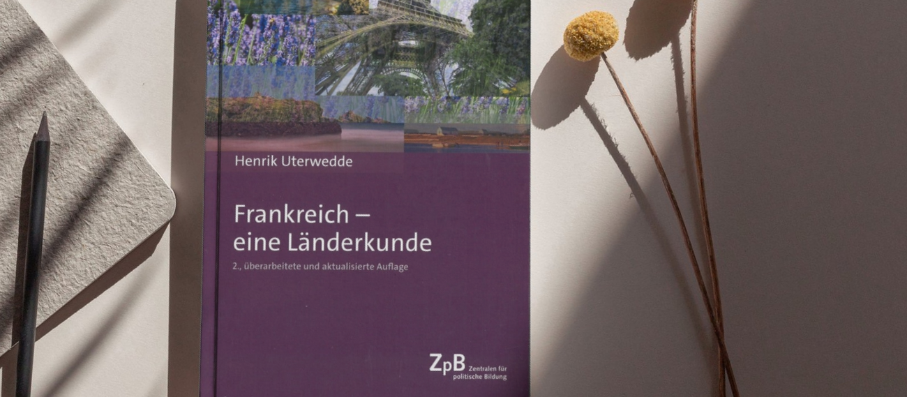 Buch Frankreich neben Stift und Blume